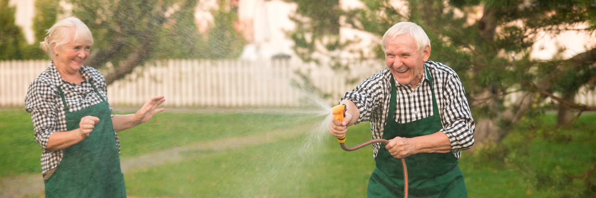 Happy Senior Couple having fun with water hose